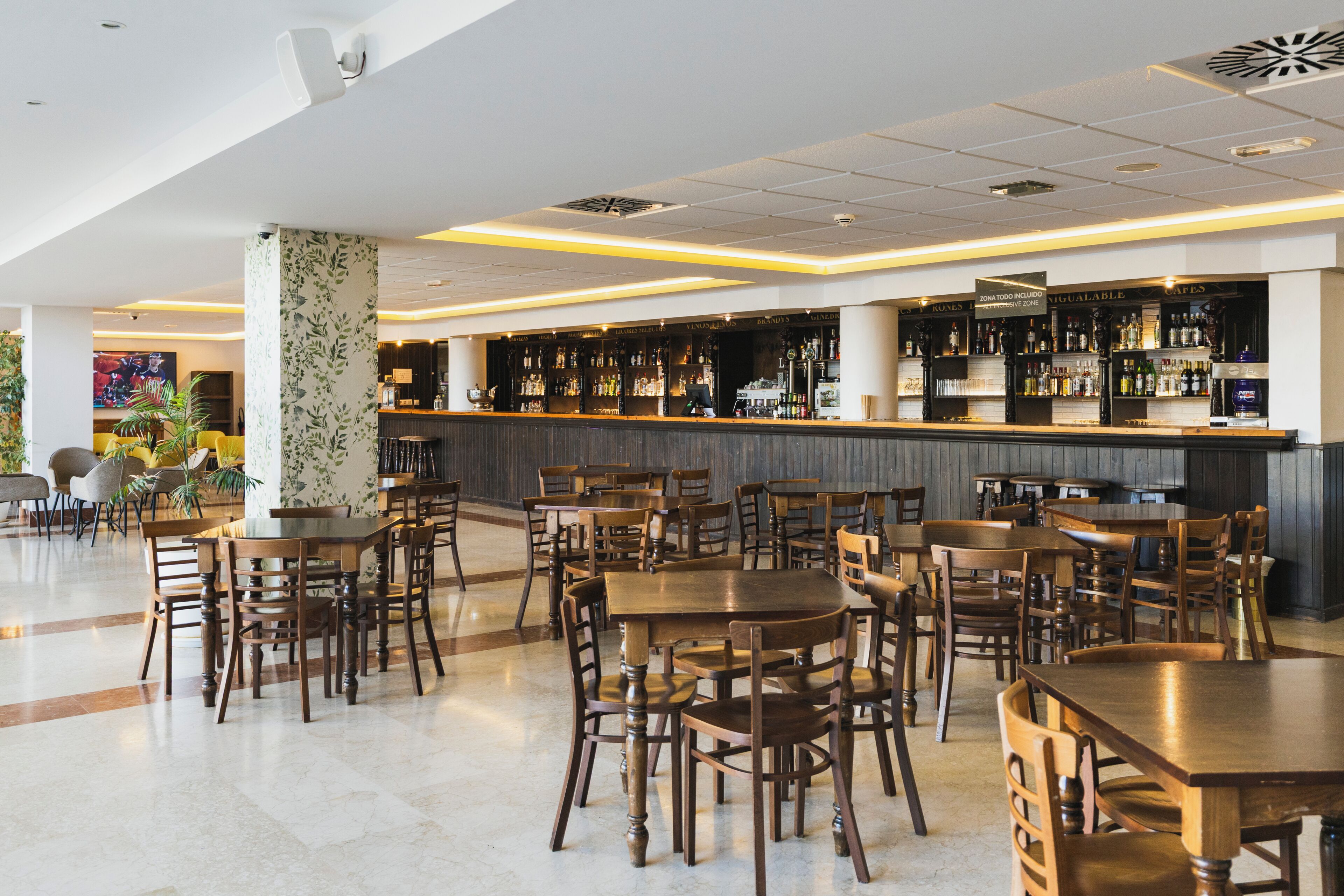 A spacious bar area with multiple seating options and a variety of liquor bottles on display.
