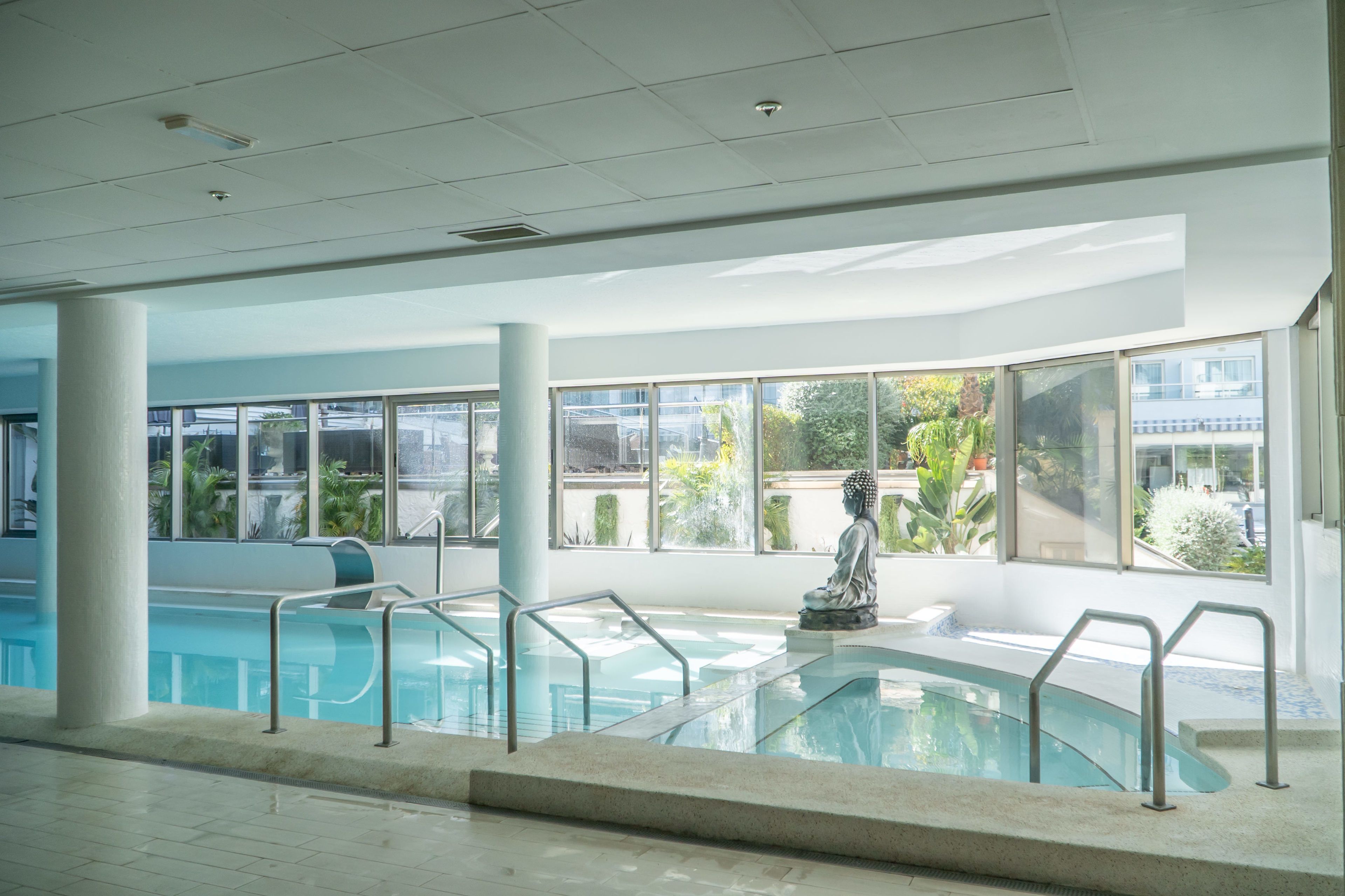 Piscina com estátua de Buda, janelas amplas e design de interiores moderno.