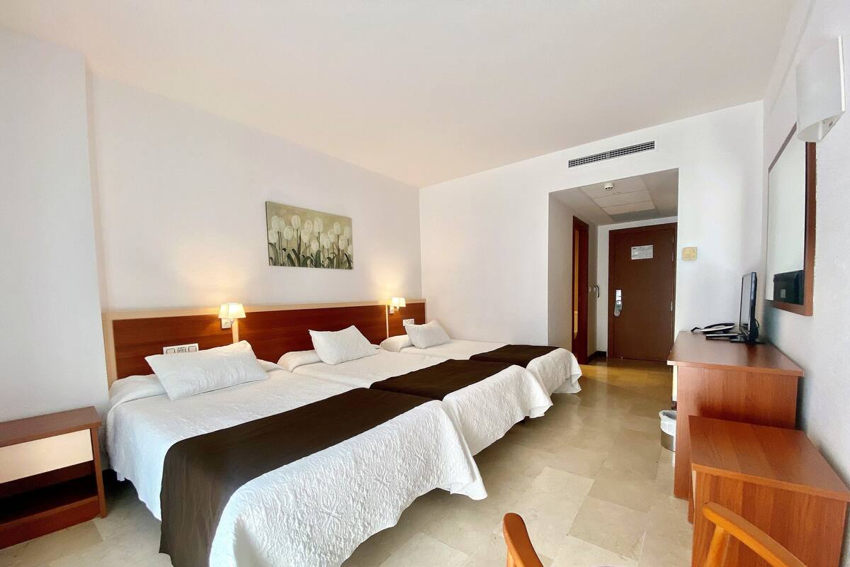 A hotel room with a large bed, bedside tables, a desk, and a chair.
