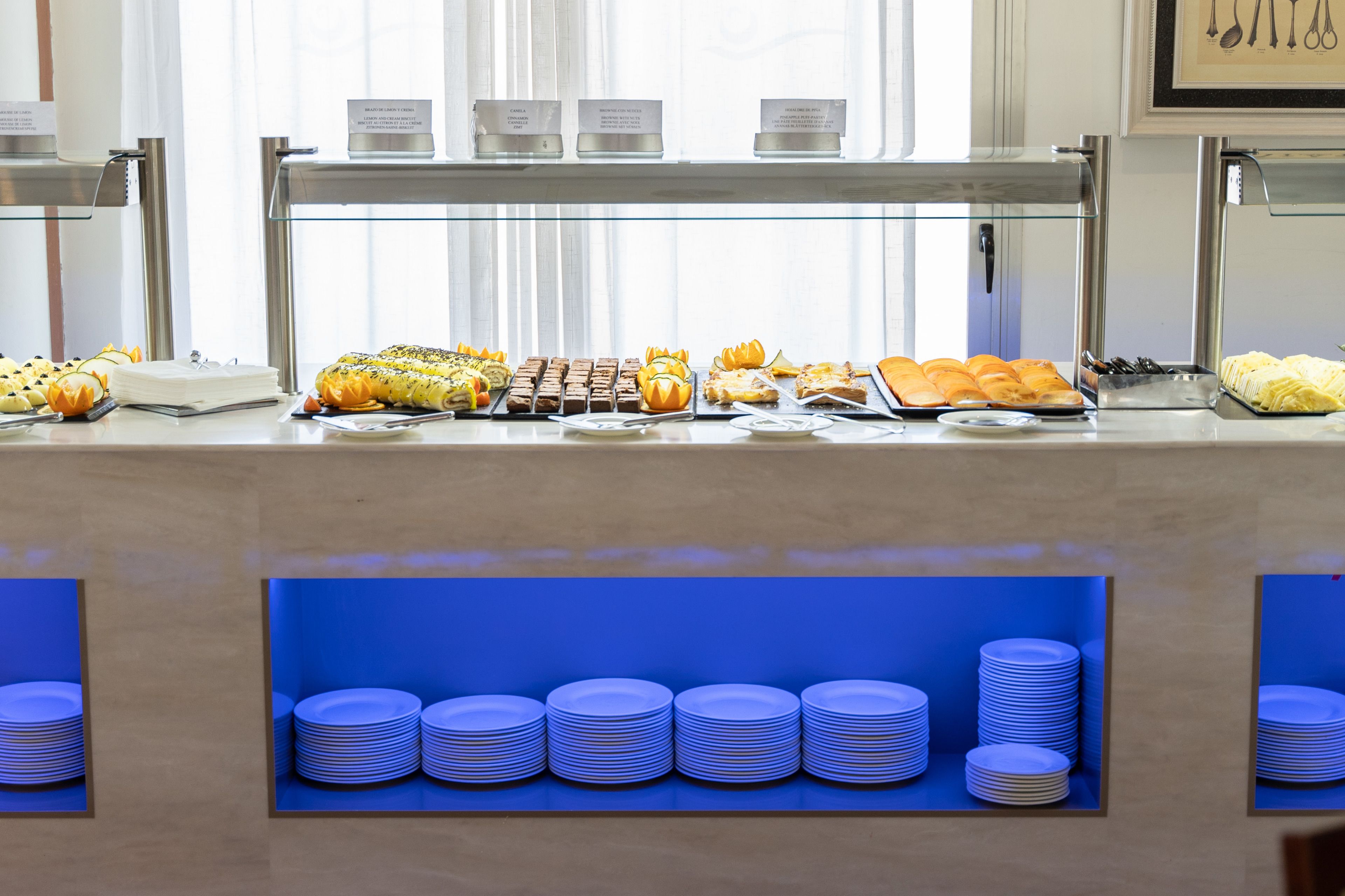 A buffet with various food items and stacked plates.