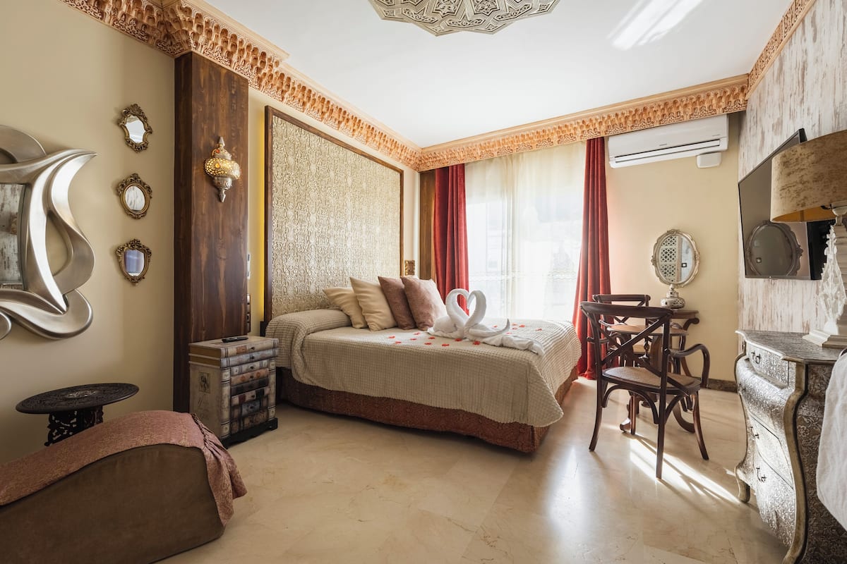 A bedroom with a bed, a desk, a chair, a dresser, and a wall with decorative elements.