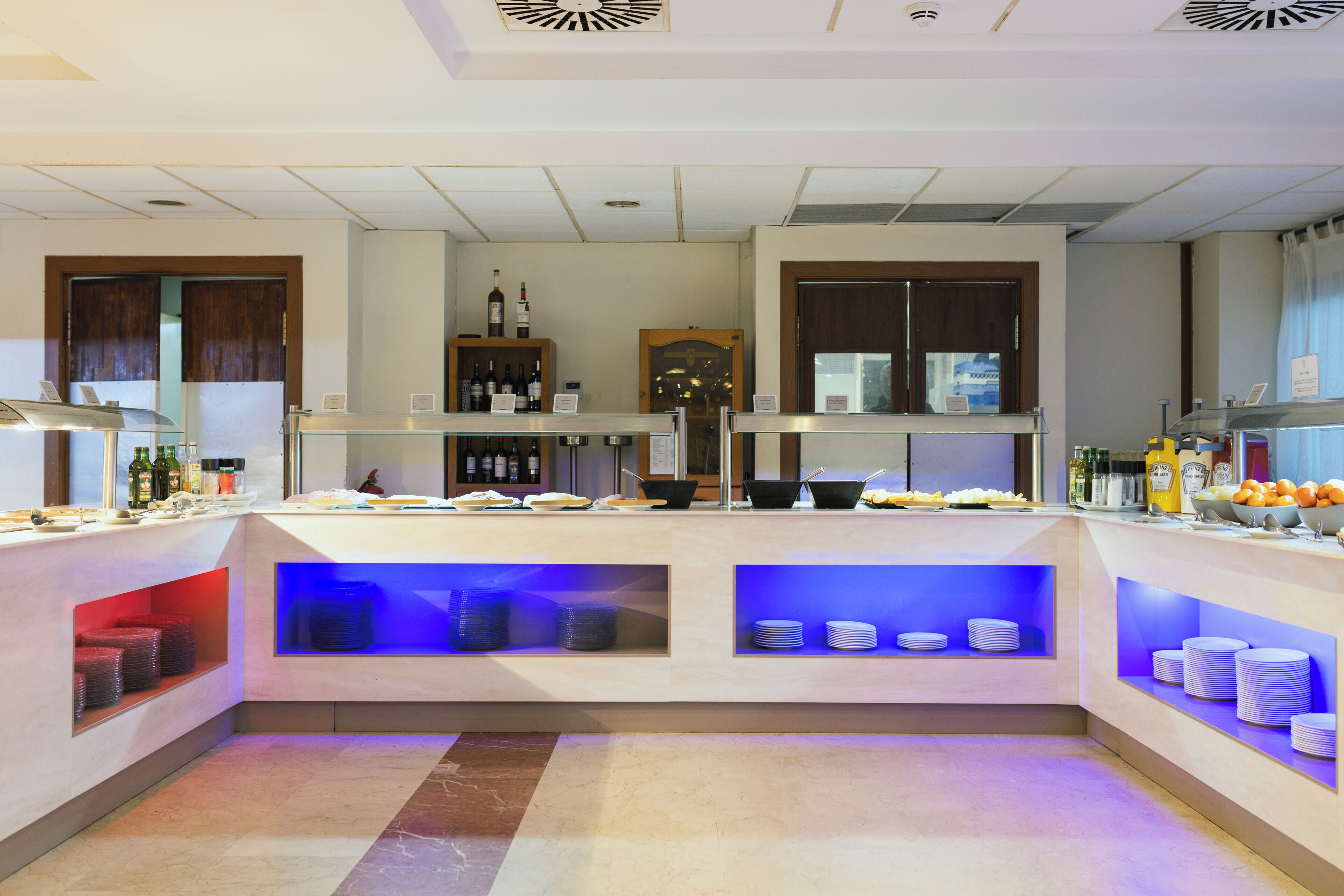 Un vestíbulo de hotel con mostrador de recepción, exhibición de vinos y zona de bufé.