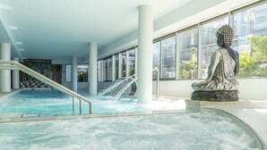 Ein Bereich mit Whirlpool, einer Statue, einer Treppe und großen Fenstern.