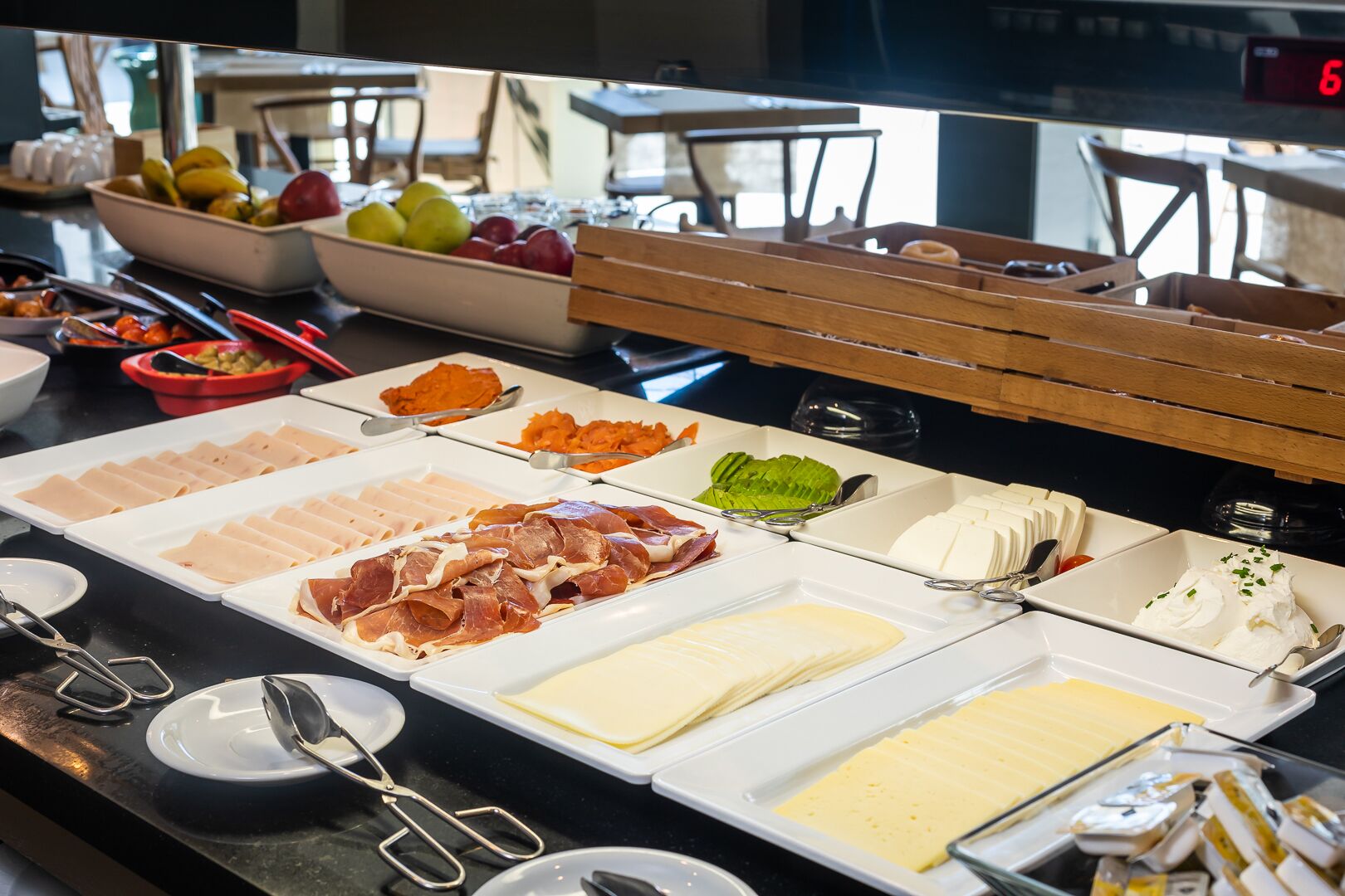 Un bufé con diversos alimentos, incluyendo carnes, quesos y frutas.