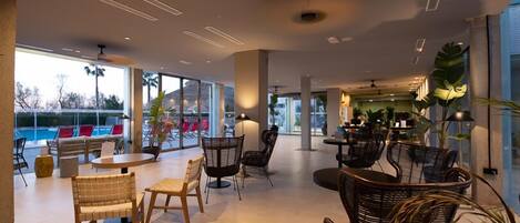 A spacious indoor area with a pool view, modern furniture, and large windows.