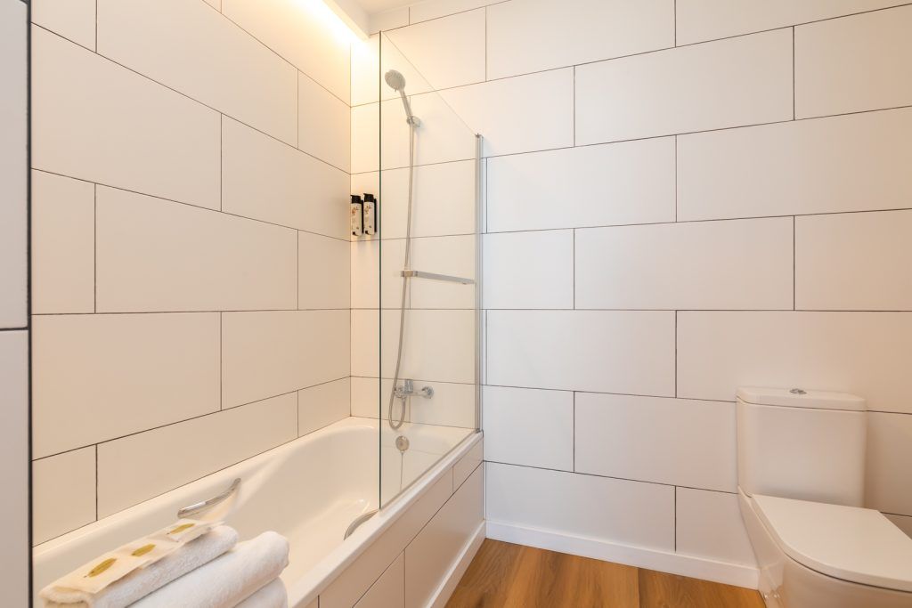 Een badkamer met een bad, toilet en douche.