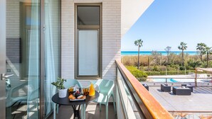 Un balcón con una mesa dispuesta para el desayuno, una piscina y vistas a la playa.