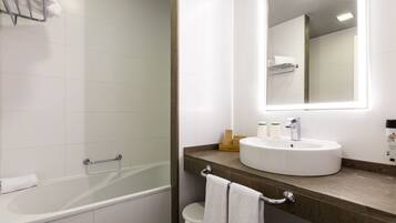A modern bathroom with a bathtub, a sink, and a large mirror.