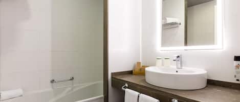 A modern bathroom with a bathtub, a sink, and a large mirror.