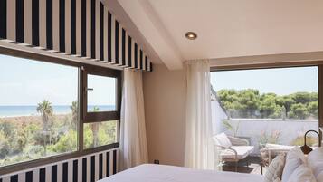 Un dormitorio con una cama grande, vista al mar y un balcón con mobiliario exterior.