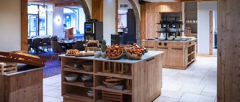 A wooden buffet setup with various food items and a seating area in the background.