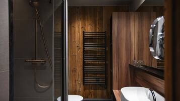 Un bagno moderno con doccia vetrata, pannello parete in legno, porta asciugamani e lavandino bianco con rubinetto cromato.