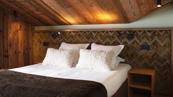 Un dormitorio con techo de madera, cama con ropa blanca y pared con patrón de espiga.