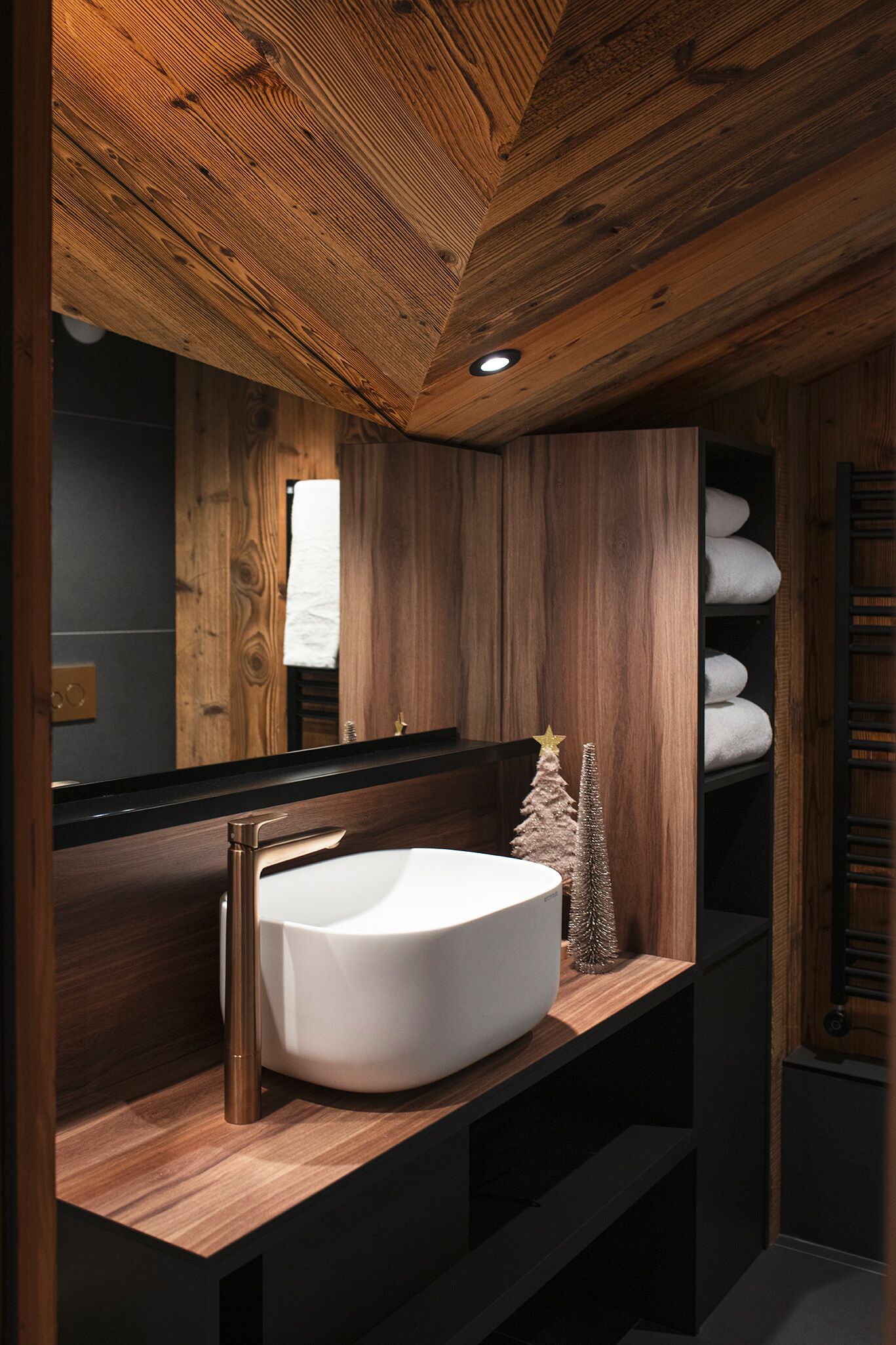 Un baño con techo de madera, un lavamanos blanco y un pequeño árbol de Navidad.