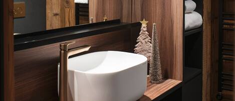 Un baño con techo de madera, un lavamanos blanco y un pequeño árbol de Navidad.