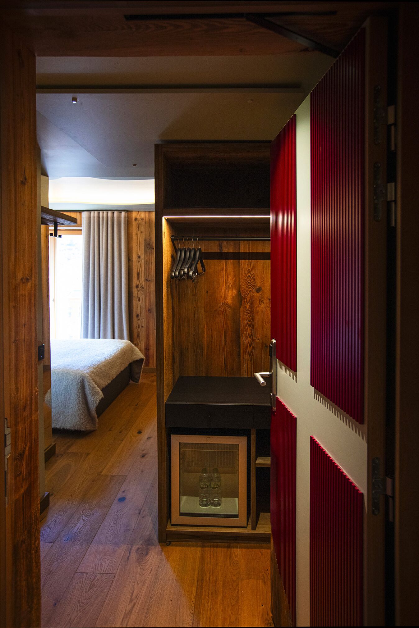 A compact bedroom with a bed, a small desk, and a wardrobe.