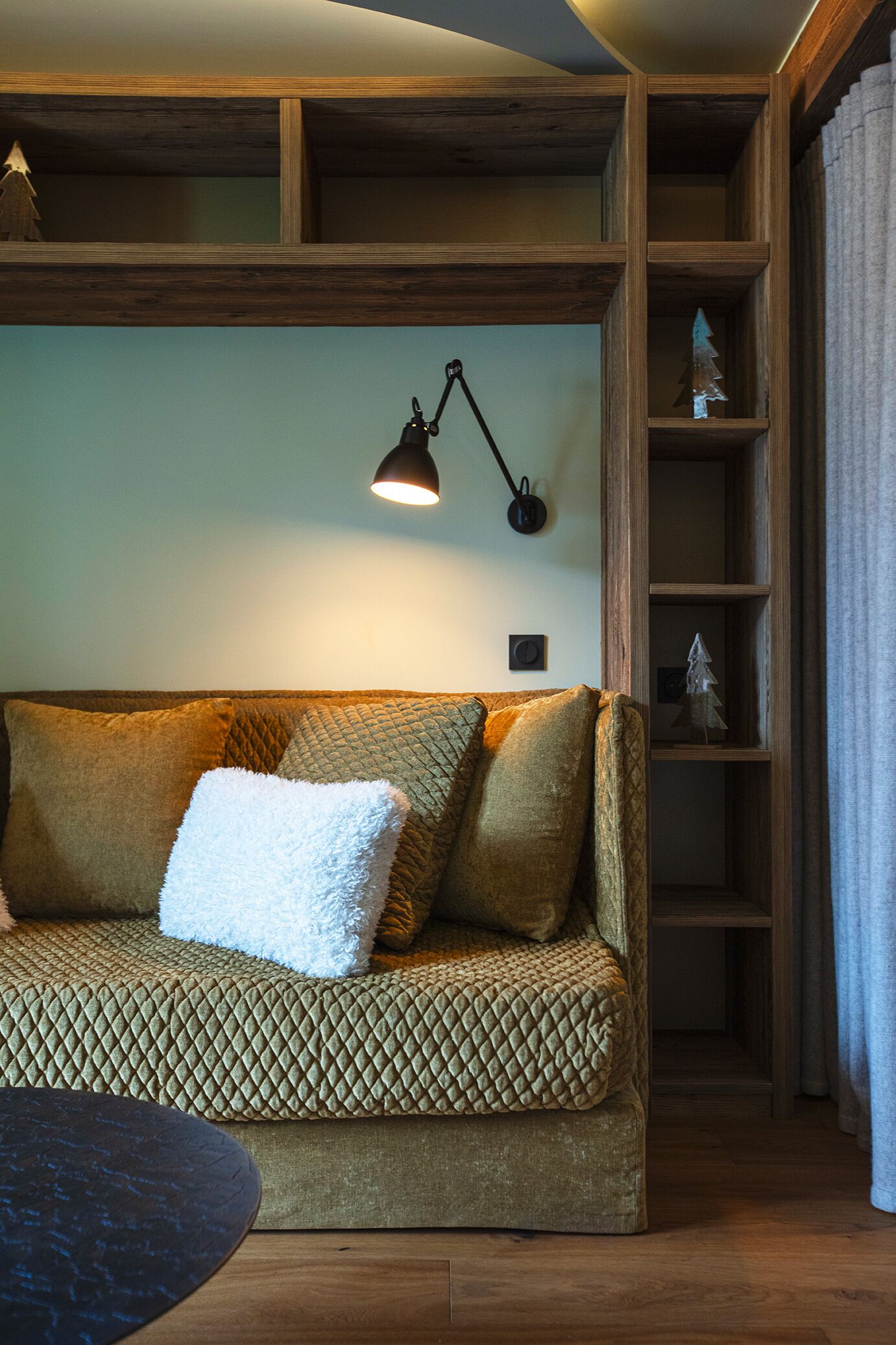 Ein gemütliches Wohnzimmer mit einer gemusterten Couch, einem kleinen Tisch und einer Wandlampe.