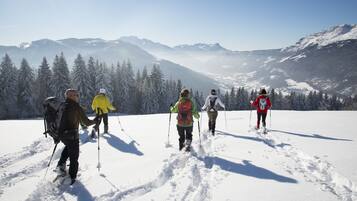 A group of people cross-country skiing on a snowy landscape with mountains in the background.