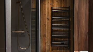 Une salle de bain moderne avec une douche à parois de verre, un mur en bois et un sol noir.