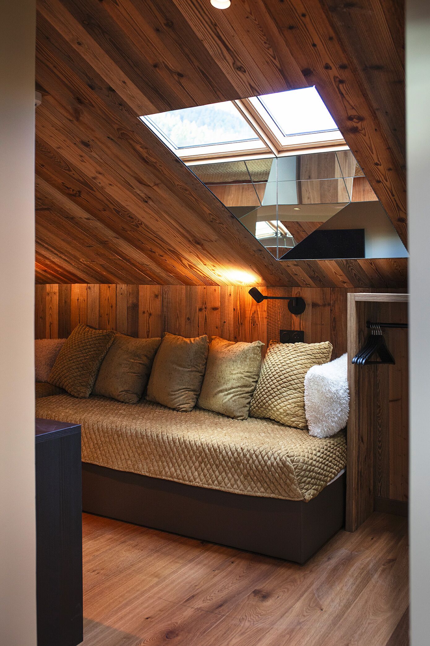 Een gezellig slaapkamer op zolder met een schuine hemel, houten wanden, een bed met een gewatteerde deken en een dakraam.