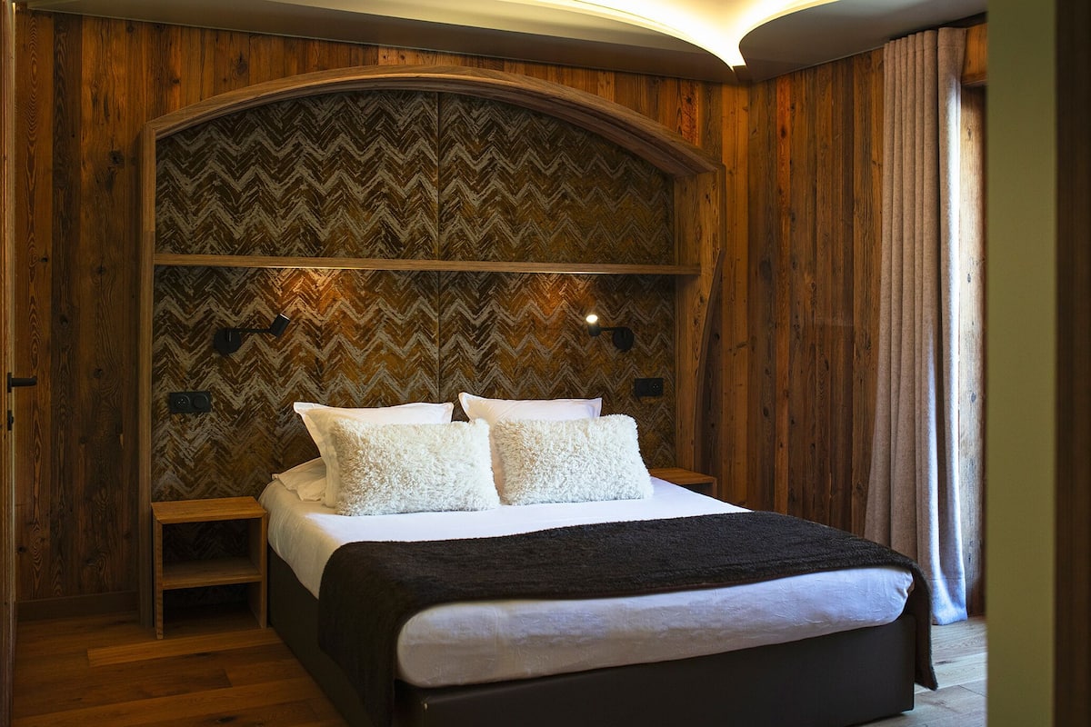 A bedroom with a wooden headboard, a bed with white bedding, and a nightstand.