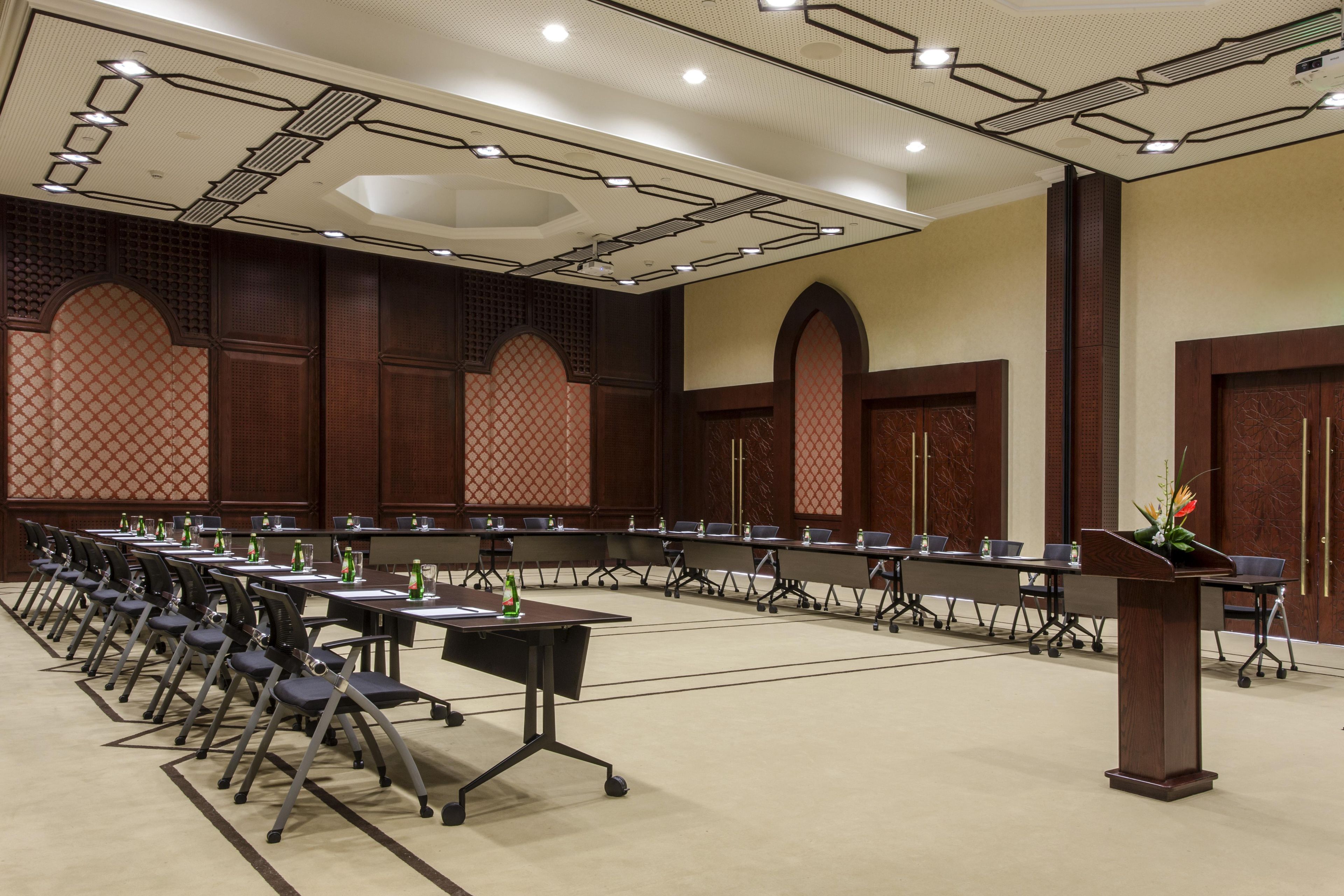 Une salle de conférence avec une longue table, des chaises et un pupitre.