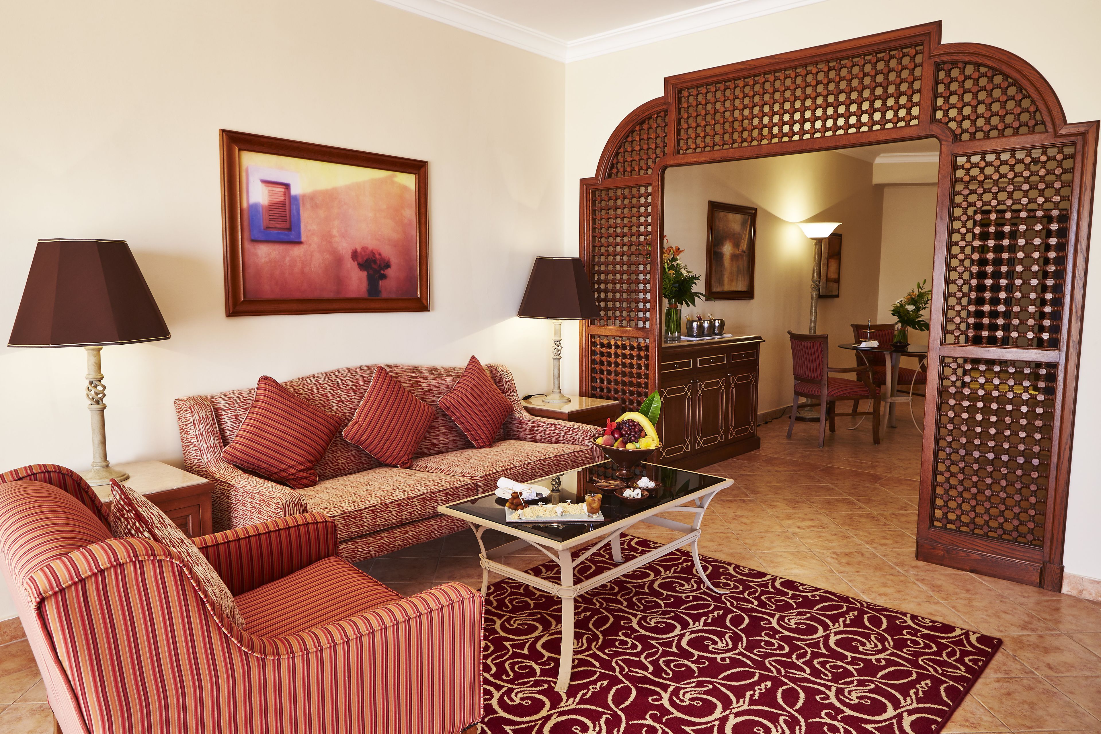 Una sala de estar con sofá, sillones, una mesa de centro y un espejo decorativo.