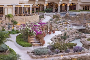 A landscaped garden with a water feature, seating areas, and a view of the hotel building.