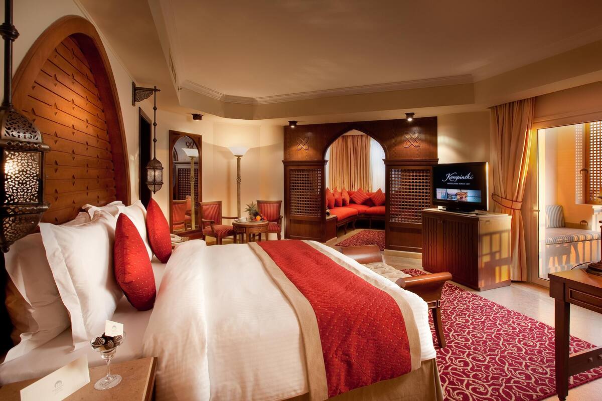 Ein Hotelzimmer mit einem großen Bett, einem Fernseher, einem Schreibtisch und einer Sitzecke mit einem roten Sofa.