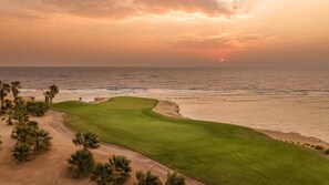 Campo de golf con vista al océano al atardecer.