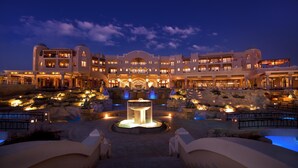 A large, multi-story hotel with a central courtyard featuring a fountain and pools.