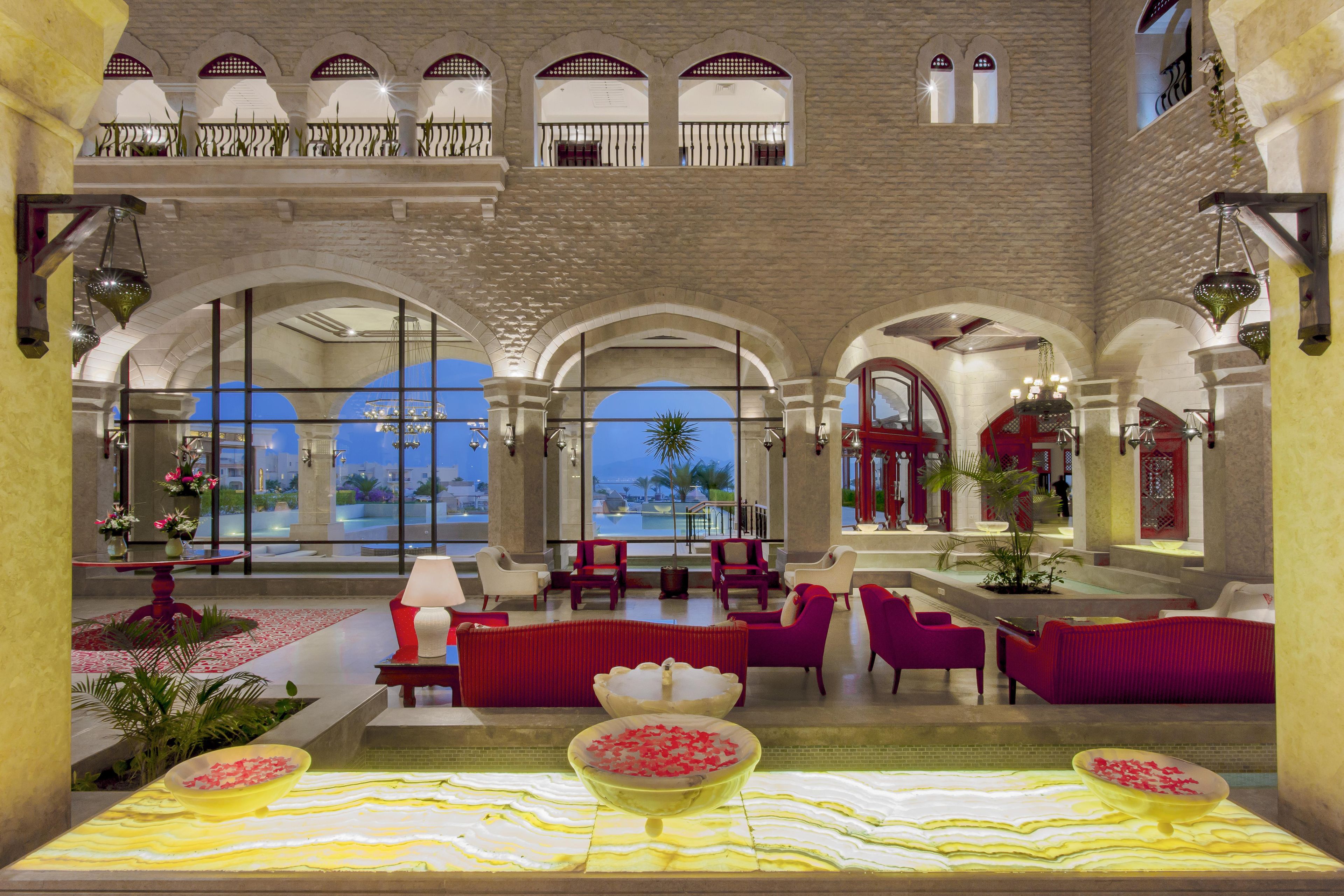 Un vestíbulo amplio con piscina, mobiliario rojo y blanco y vistas al área de la piscina.