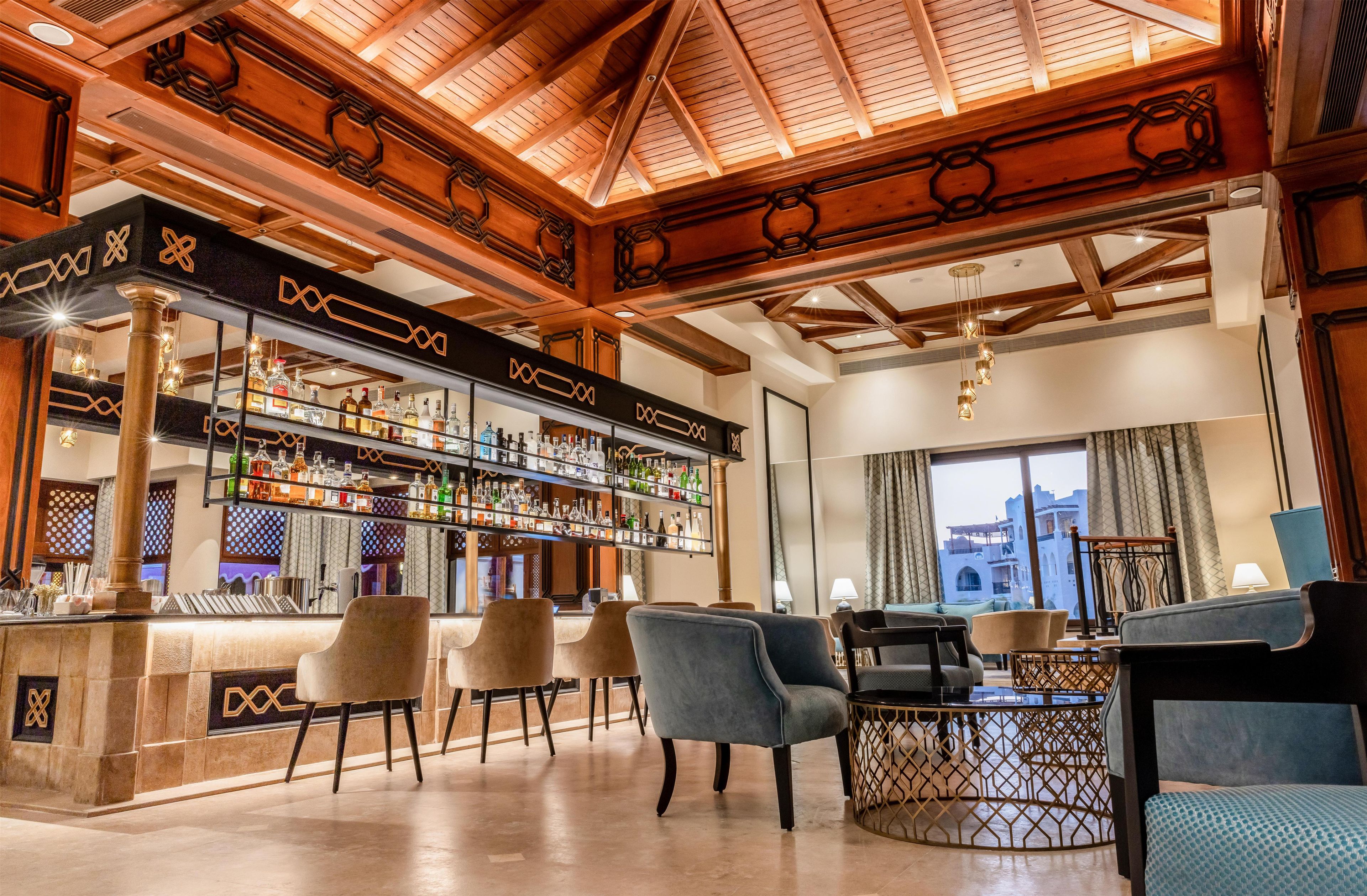 A bar area with a wooden ceiling and a bar counter stocked with various bottles.