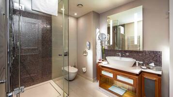 Un baño moderno con ducha envuelta en vidrio, un espejo grande y un mueble de tocador con lavamanos y almacenamiento.