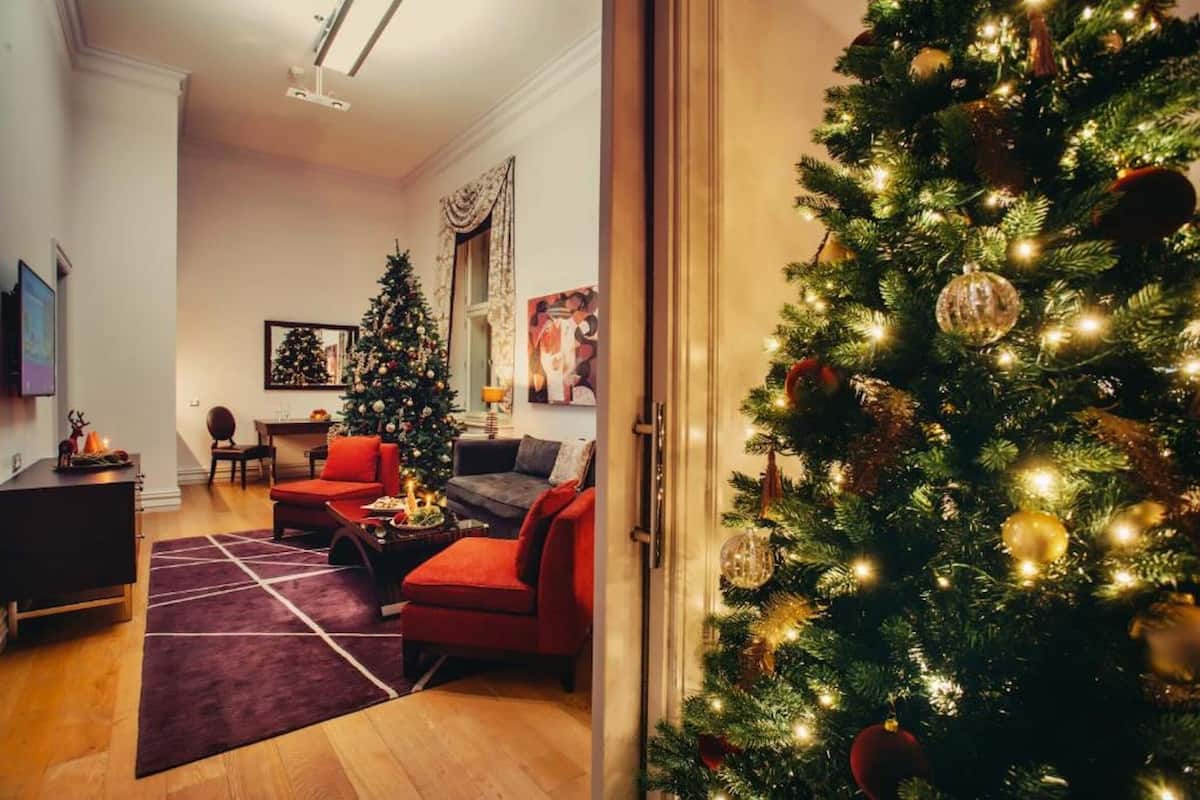 A living room with a Christmas tree, red sofas, and a fireplace.