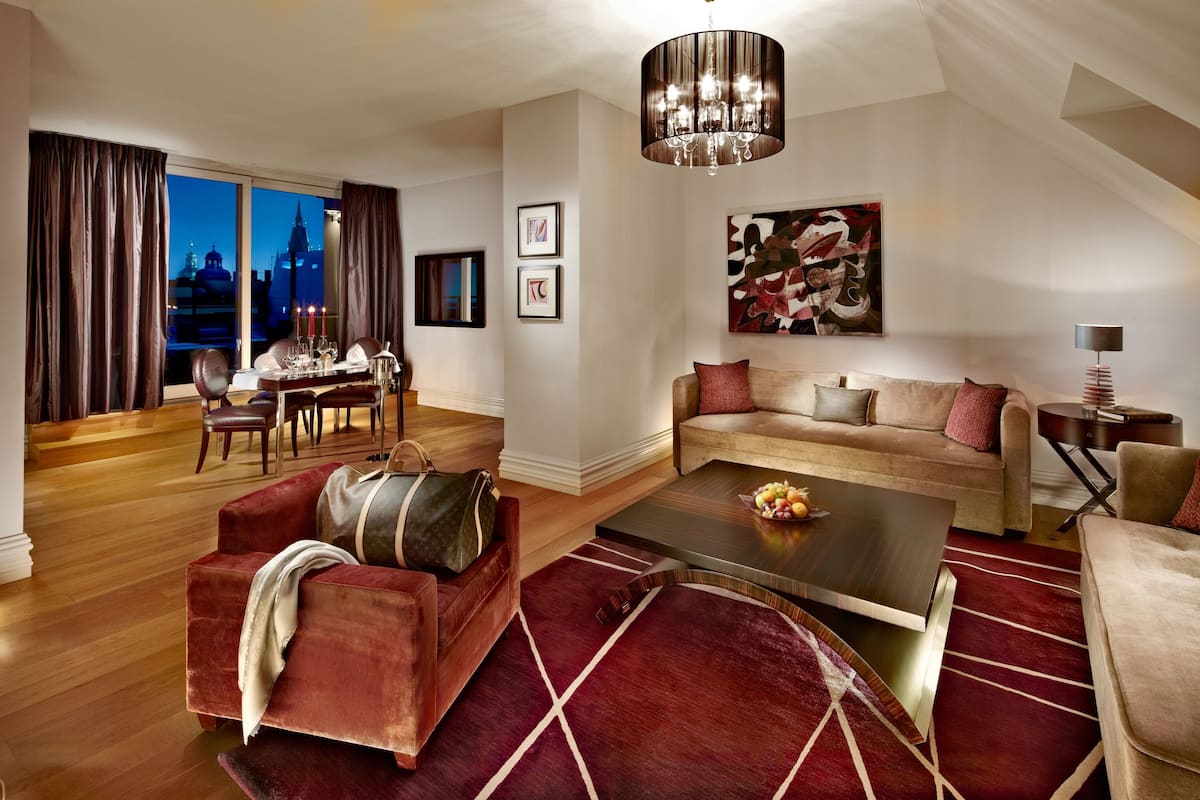 A modern living room with a sofa, coffee table, and a dining area with a table and chairs.