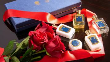 A luxury gift set with a blue box, red ribbon, and various toiletries including a shower gel, conditioner, and luxury soap.