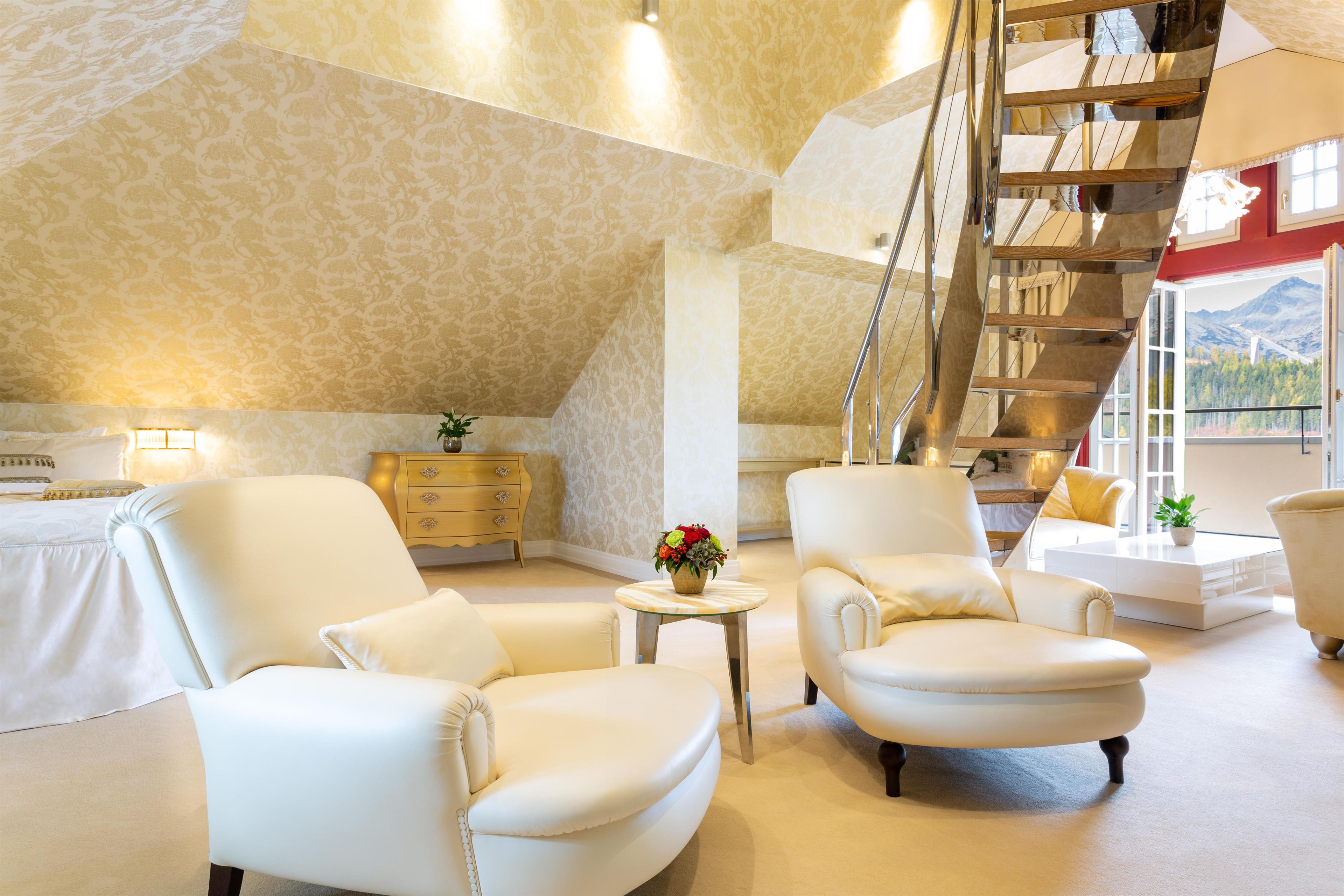 A spacious living room with a high ceiling, a staircase, and a view of mountains through the windows.