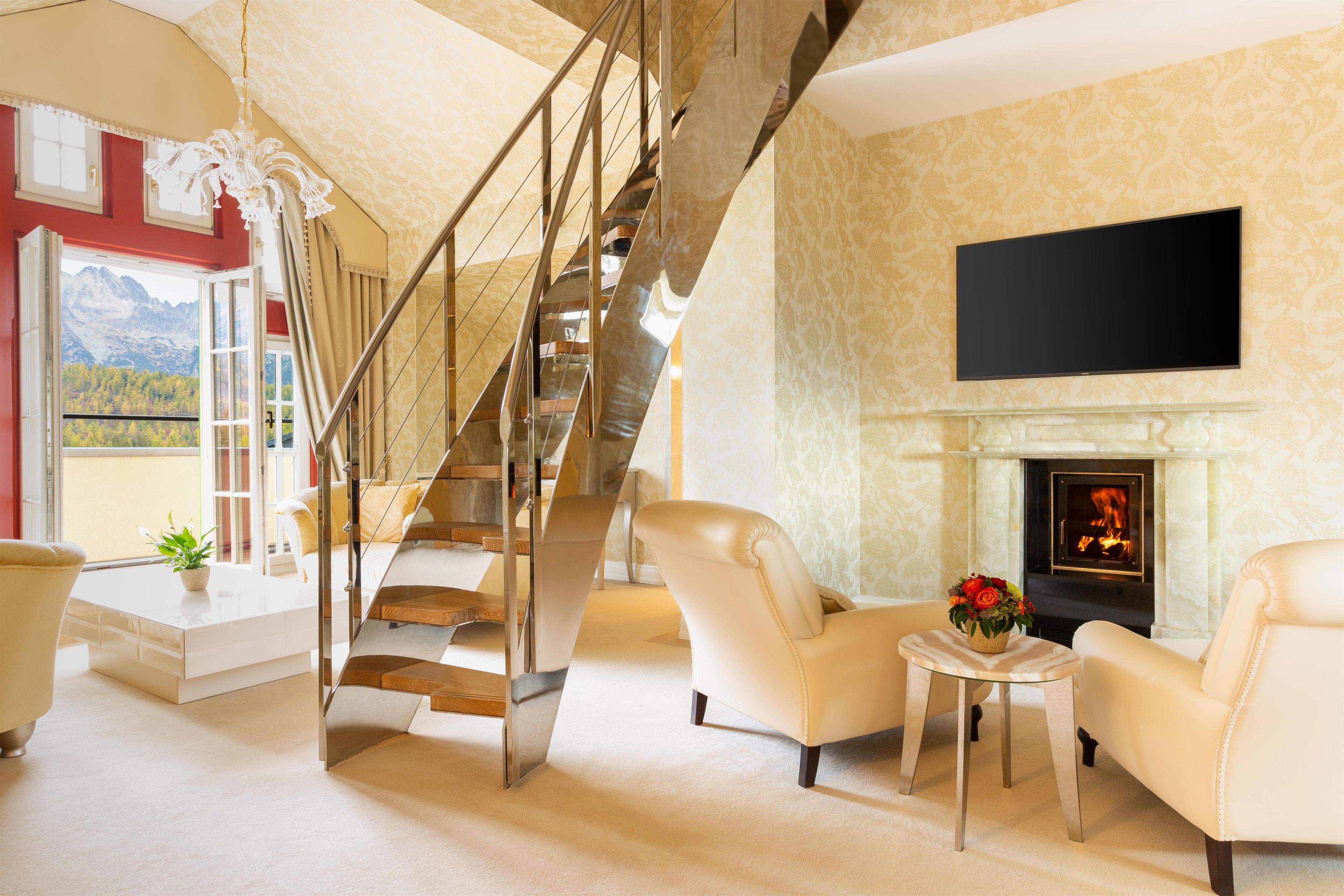 A spacious living area with a staircase, a fireplace, and a television mounted on the wall.