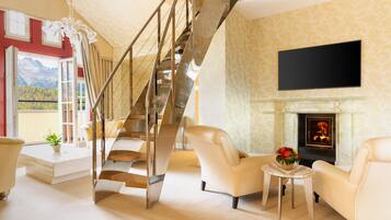 A spacious living area with a staircase, a fireplace, and a television mounted on the wall.
