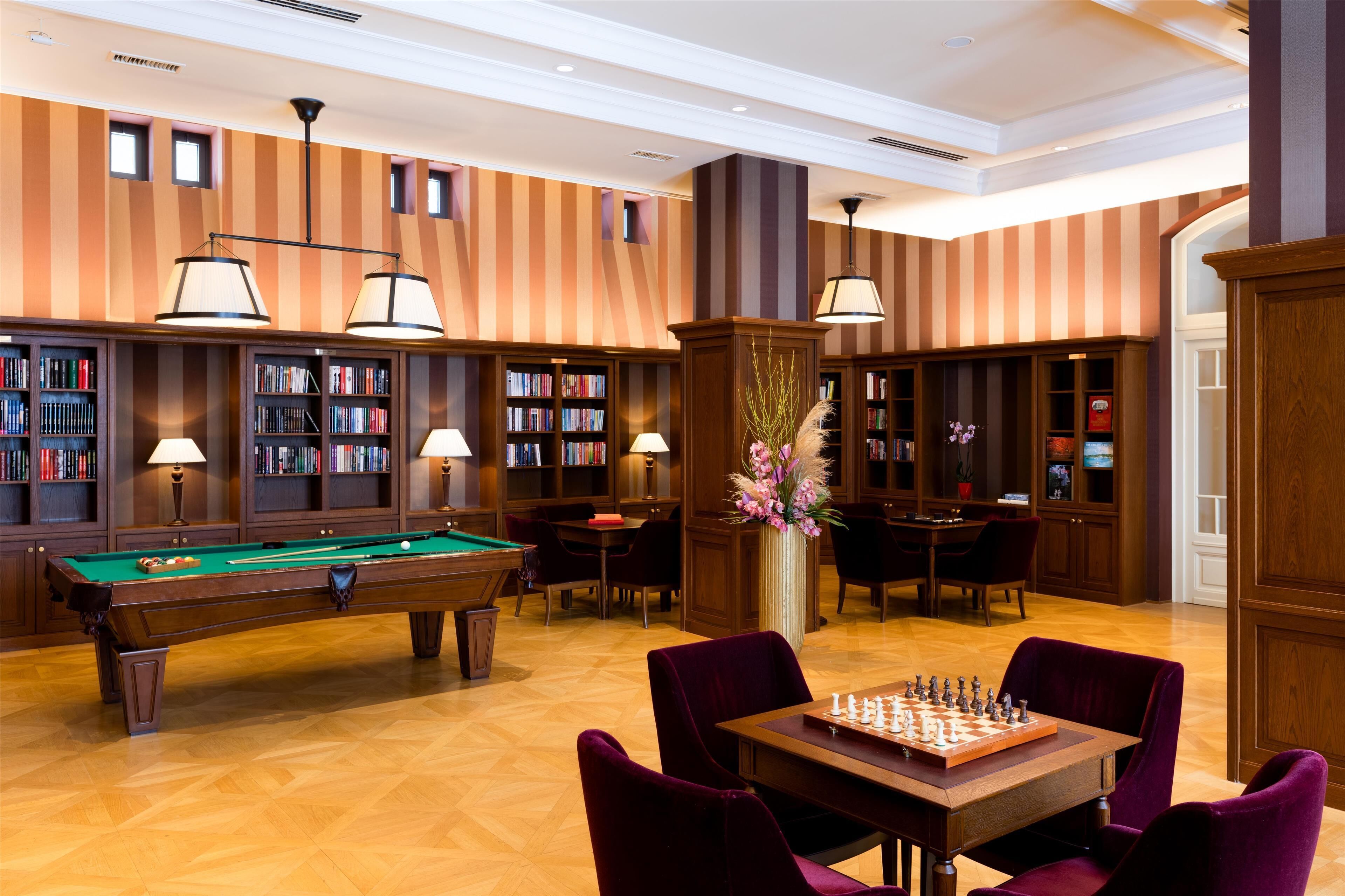 A library with a pool table, chess table, and bookshelves.