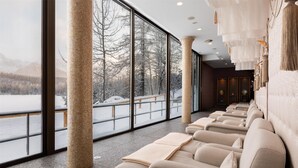 A spa area with large windows, a row of massage chairs, and a view of a snowy landscape.