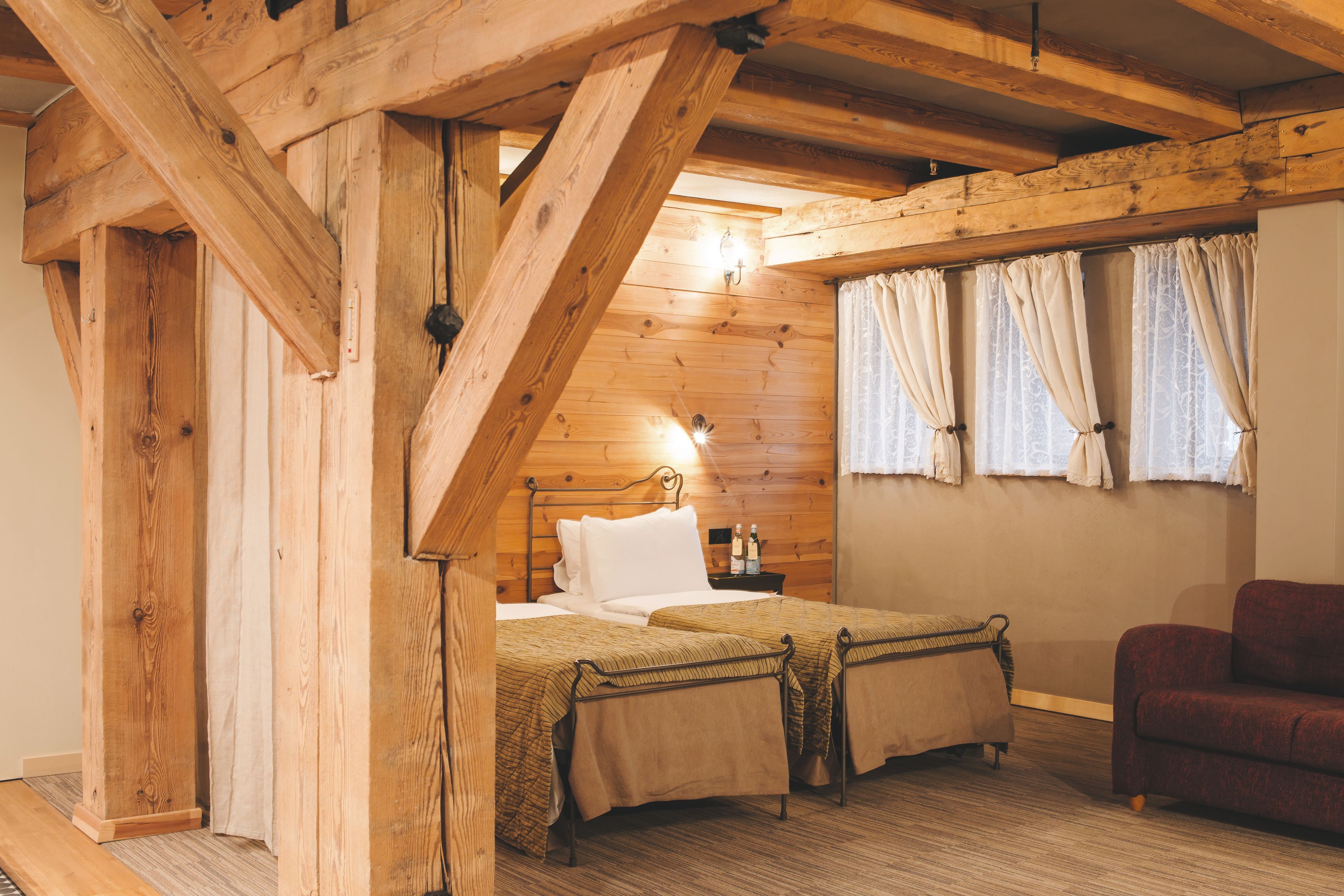 Une pièce chaleureuse, avec des murs en bois, comprenant un lit, une table de chevet et un canapé.