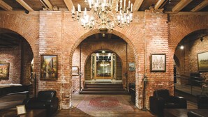 A spacious lobby with brick walls, a chandelier, leather seating, and a large rug.