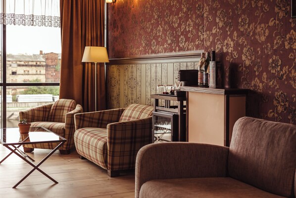 A cozy living room with plaid sofas, a coffee table, and a fireplace. - Promenade Hotel Liepaja (Liepaja)