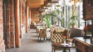A spacious indoor area with brick walls, multiple seating arrangements, and potted plants.