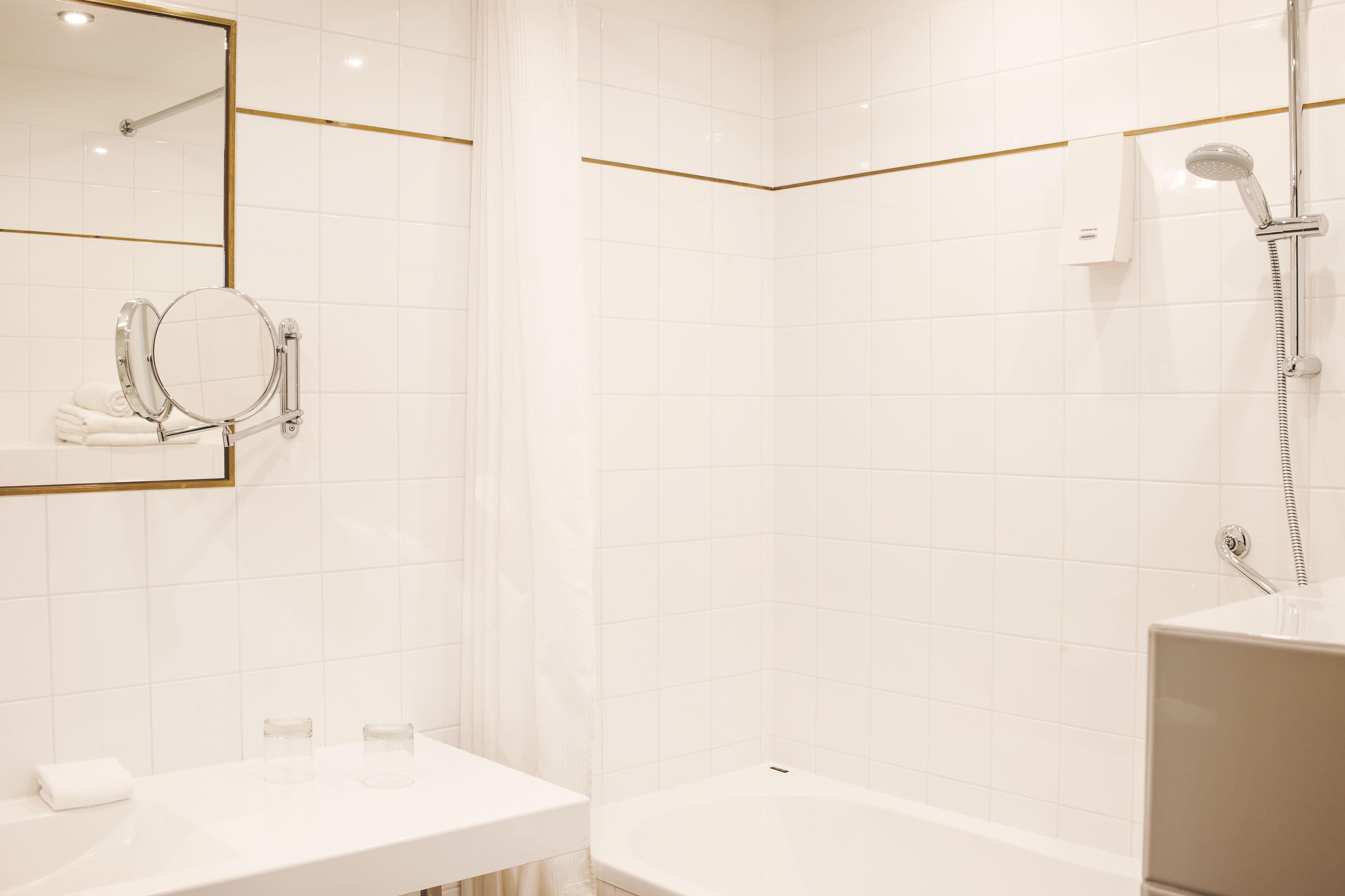 Un baño moderno con lavamanos, espejo y ducha blancos.