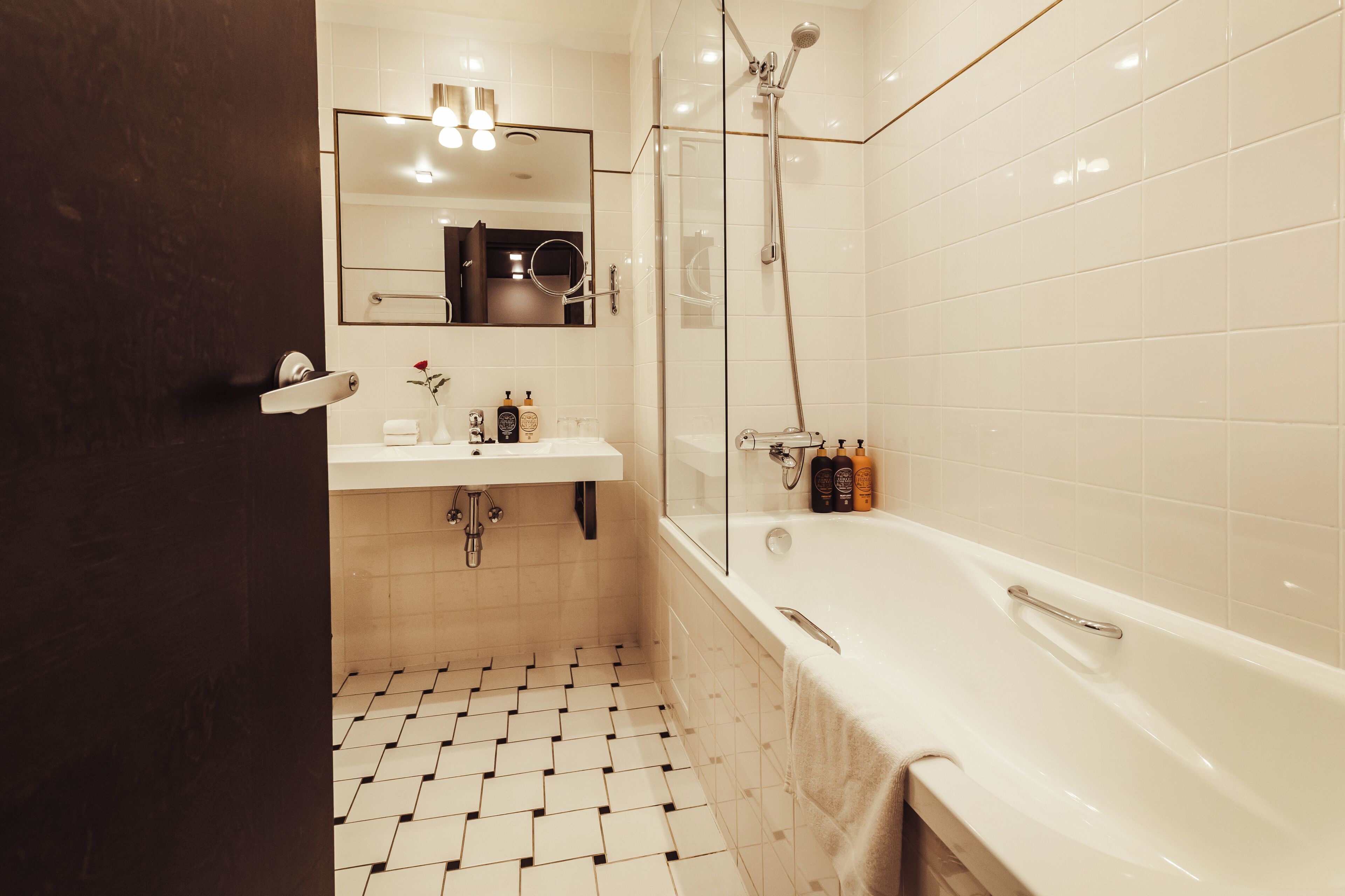 Ein modernes Badezimmer mit Waschbecken, Spiegel und Badewanne in Weiß.