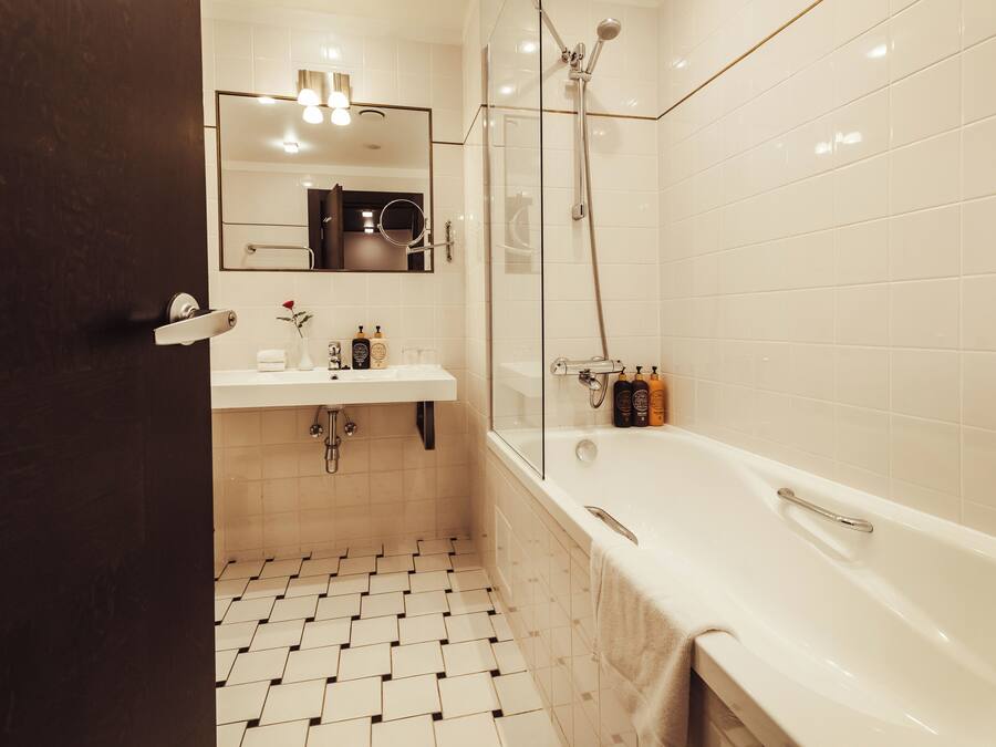 Ein modernes Badezimmer mit Waschbecken, Spiegel und Badewanne in Weiß.