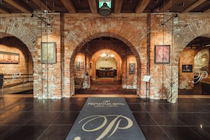 A hotel lobby with a brick archway, a chandelier, and a reception desk. - Promenade Hotel Liepaja (Liepaja)